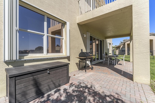 view of patio / terrace with grilling area, a balcony, and fence