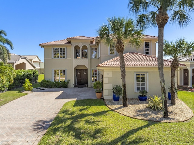 mediterranean / spanish home with stucco siding, a front yard, and a tile roof