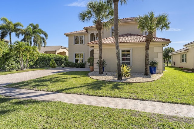 mediterranean / spanish-style home featuring stucco siding, a tile roof, and a front yard