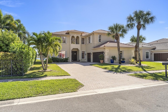 mediterranean / spanish house featuring stucco siding, a tile roof, decorative driveway, and a front lawn