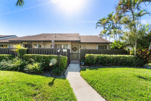 ranch-style home featuring a front lawn, a fenced front yard, a gate, and stucco siding