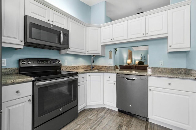 kitchen with appliances with stainless steel finishes, white cabinetry, a sink, and light wood finished floors