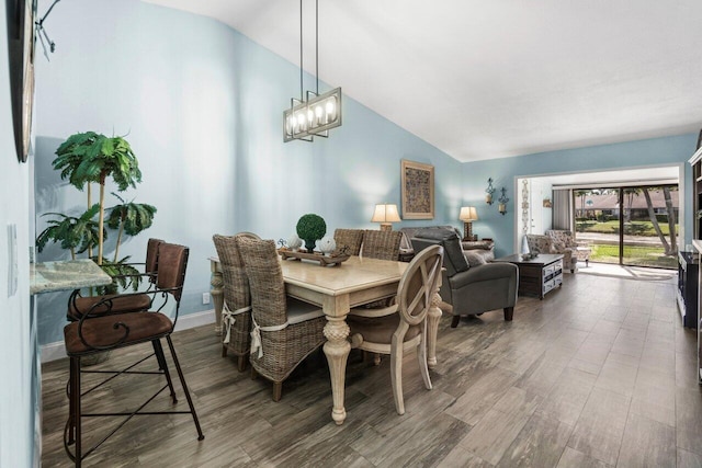 dining room featuring vaulted ceiling, baseboards, wood finished floors, and an inviting chandelier