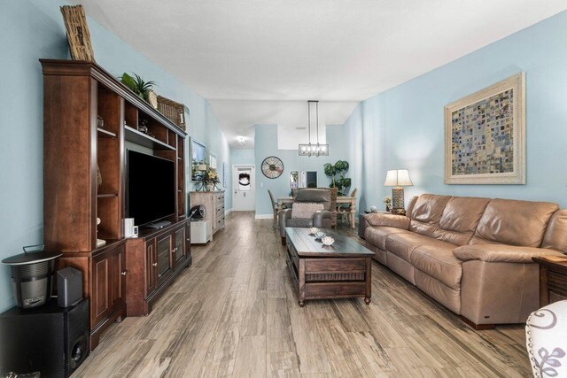 living room featuring lofted ceiling, light wood finished floors, and a chandelier