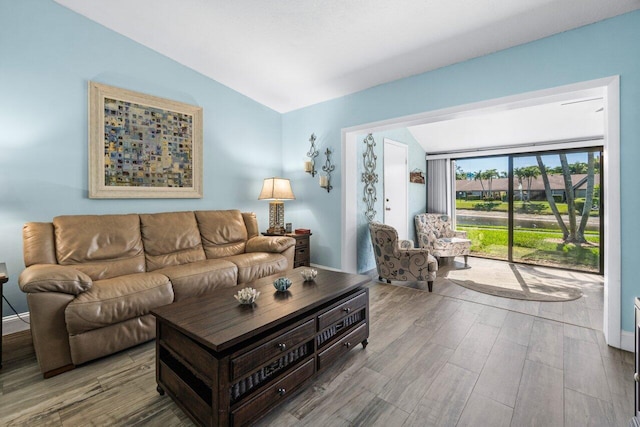 living room featuring baseboards, vaulted ceiling, and wood finished floors