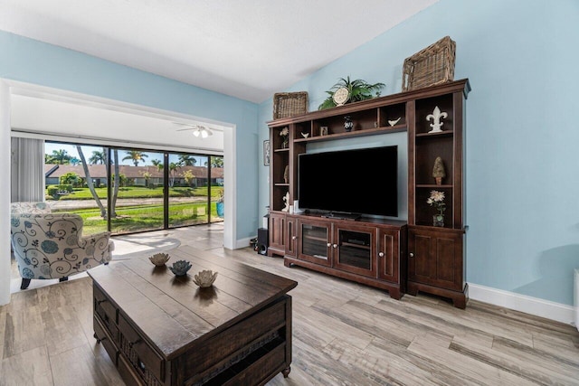 living area featuring wood finished floors, a ceiling fan, and baseboards