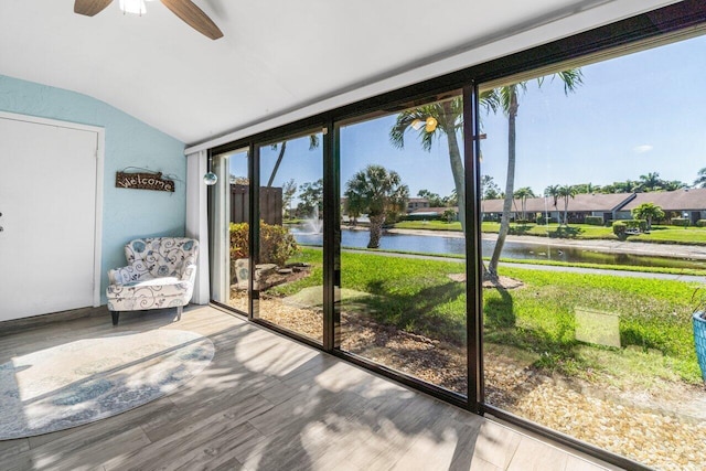 unfurnished sunroom with a ceiling fan, a water view, and vaulted ceiling