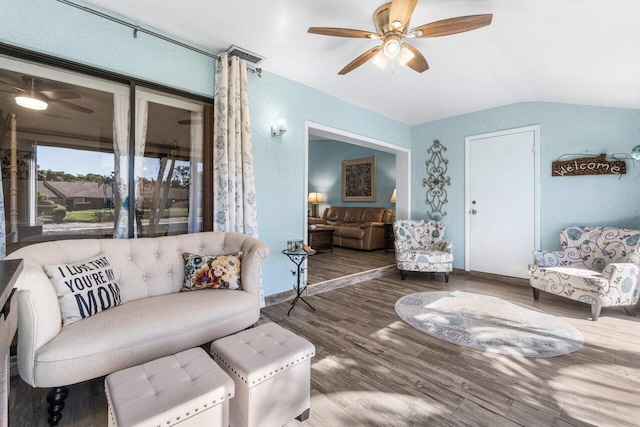 living room with a ceiling fan, vaulted ceiling, and wood finished floors