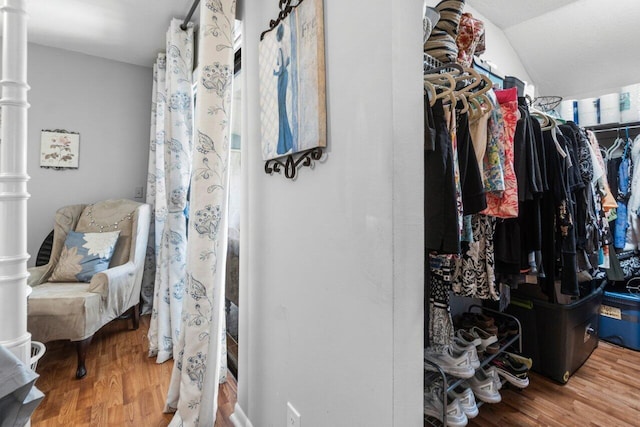 spacious closet featuring lofted ceiling, ornate columns, and wood finished floors