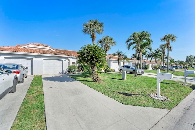 view of front of home featuring an attached garage, a tile roof, concrete driveway, stucco siding, and a front yard