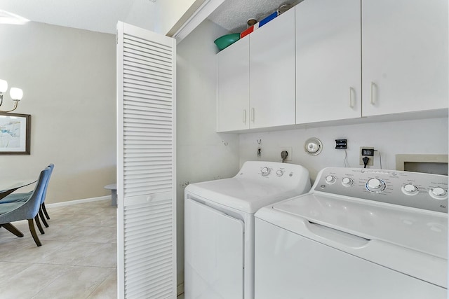 washroom featuring washing machine and dryer, cabinet space, baseboards, and light tile patterned flooring