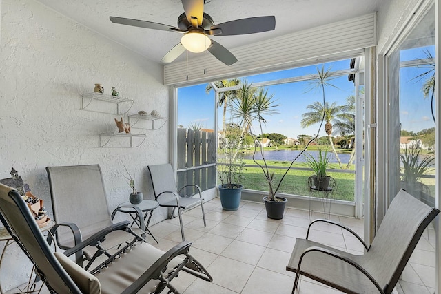 sunroom featuring a water view and a ceiling fan