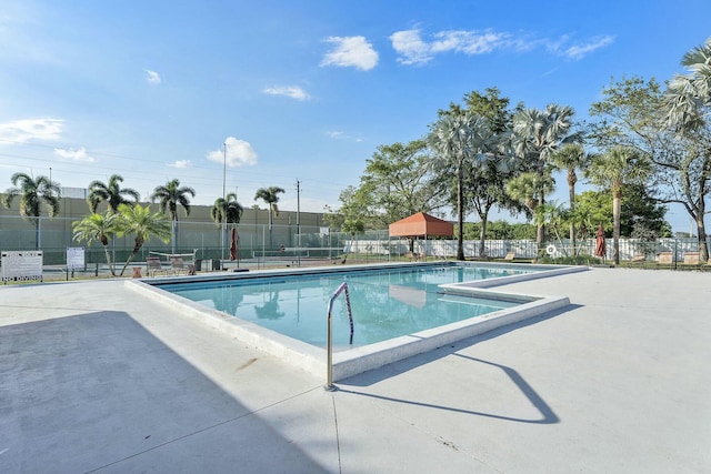 community pool with a patio and fence