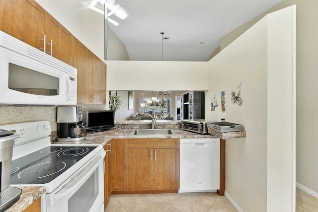 kitchen with light tile patterned floors, white appliances, brown cabinetry, and a sink