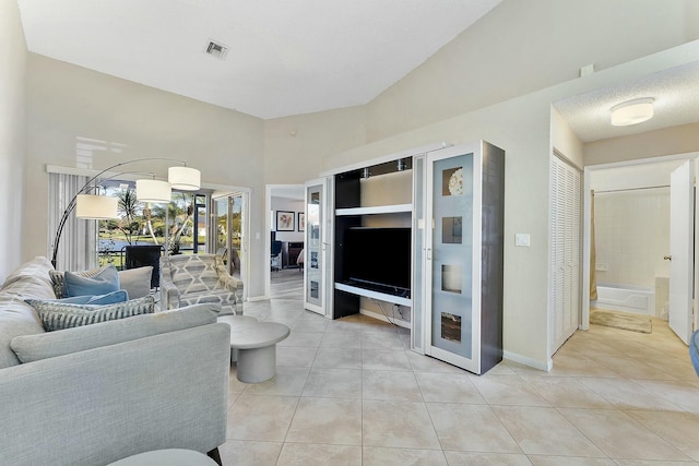 living room with light tile patterned floors, baseboards, visible vents, and a textured ceiling