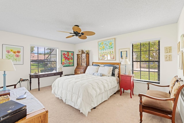 bedroom with a textured ceiling, baseboards, a ceiling fan, and light colored carpet