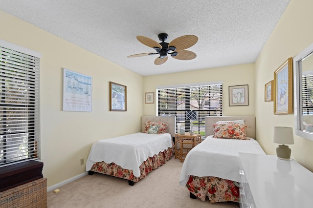 carpeted bedroom with a textured ceiling, baseboards, and a ceiling fan