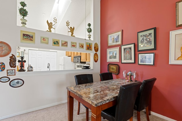 dining space with a high ceiling, carpet flooring, and baseboards