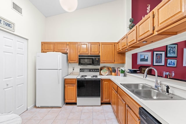 kitchen featuring visible vents, electric range oven, freestanding refrigerator, black microwave, and a sink