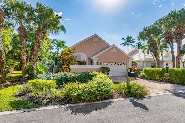 view of front of property featuring driveway, an attached garage, and stucco siding