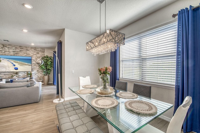 dining room with baseboards, a textured ceiling, visible vents, and wood finished floors