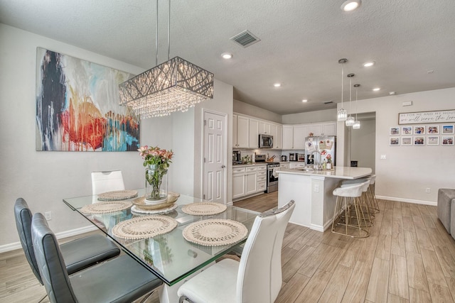 dining area featuring recessed lighting, visible vents, a textured ceiling, light wood-type flooring, and baseboards