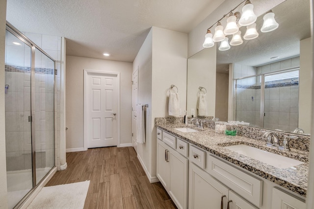 800 SE Villandry Way, Port Saint Lucie, FL 34984 - bathroom featuring a textured ceiling, a stall shower, wood finished floors, double vanity, and a chandelier