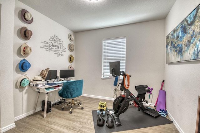 office space featuring a textured wall, a textured ceiling, baseboards, and wood finished floors