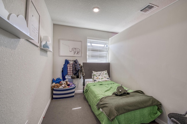 carpeted bedroom with baseboards, visible vents, a textured ceiling, and a textured wall