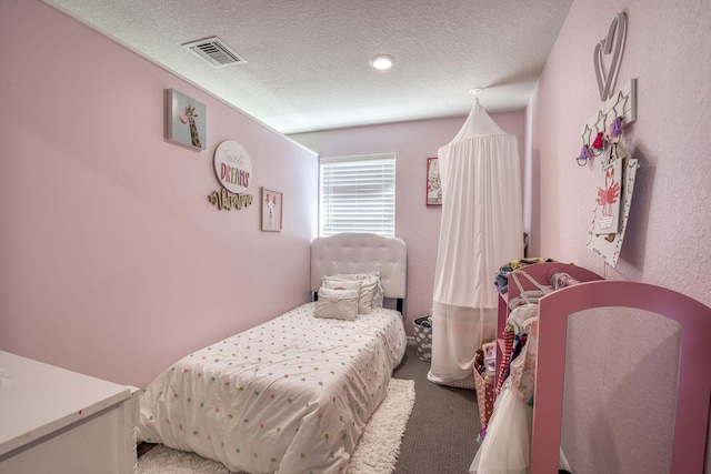 bedroom featuring light carpet, visible vents, a textured ceiling, and a textured wall