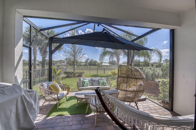 view of patio / terrace with a rural view, a lanai, outdoor lounge area, fence, and a grill