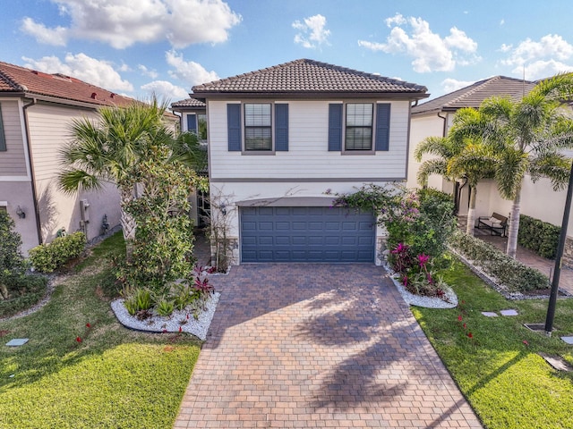 view of front of house featuring an attached garage, a tiled roof, decorative driveway, stucco siding, and a front yard