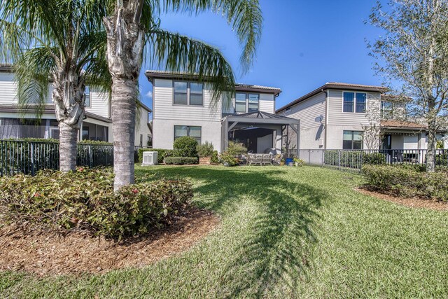 rear view of property with central air condition unit, a fenced backyard, and a yard