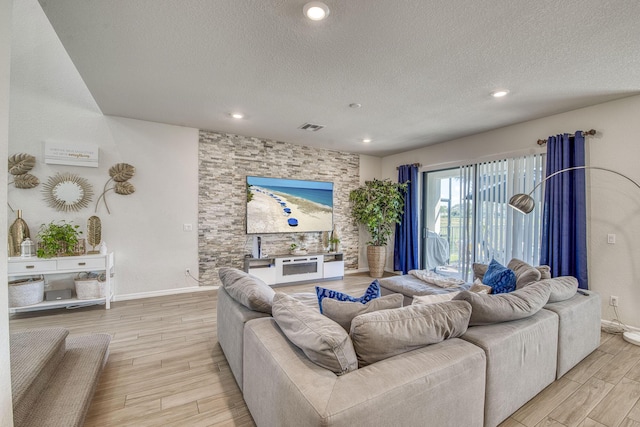 living area featuring recessed lighting, visible vents, light wood-style floors, a textured ceiling, and baseboards