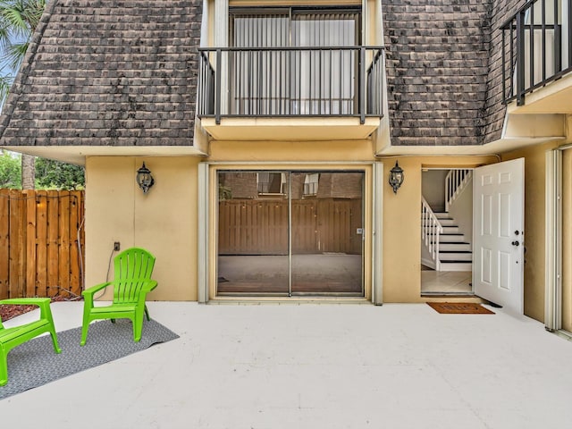 view of exterior entry with driveway, fence, a patio, and stucco siding