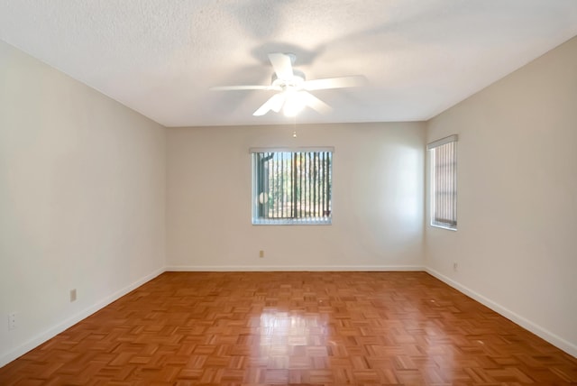 unfurnished room with a healthy amount of sunlight, ceiling fan, baseboards, and a textured ceiling