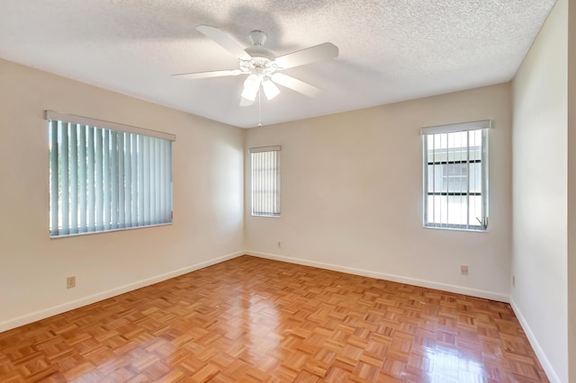 spare room with a textured ceiling, a ceiling fan, and baseboards