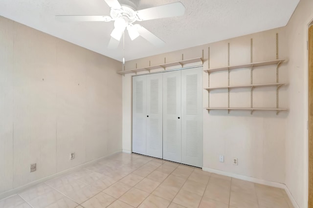 unfurnished bedroom with a ceiling fan, a closet, a textured ceiling, and baseboards