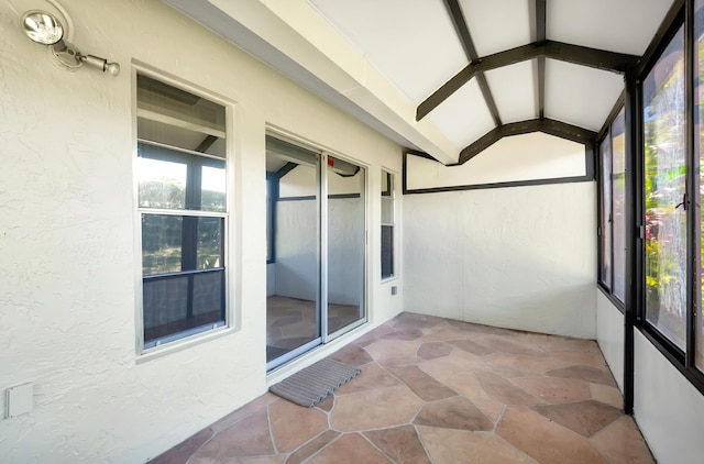 unfurnished sunroom with lofted ceiling with beams