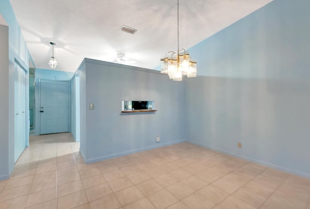 empty room with light tile patterned floors, baseboards, visible vents, a textured ceiling, and a chandelier