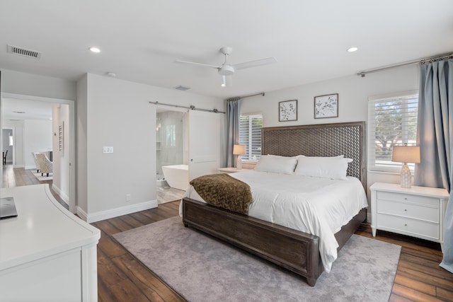 bedroom with a barn door, multiple windows, visible vents, and dark wood finished floors