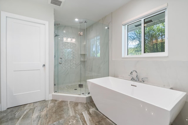 bathroom with marble finish floor, visible vents, a freestanding bath, and a shower stall