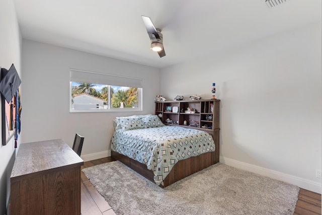 bedroom featuring ceiling fan, wood finished floors, visible vents, and baseboards