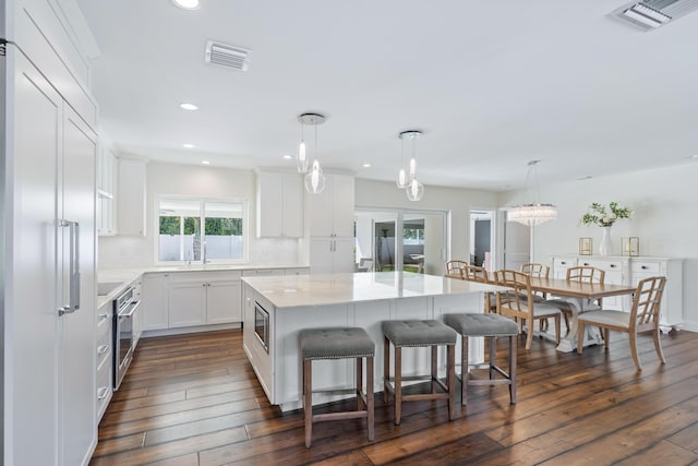 kitchen featuring a kitchen island, visible vents, a breakfast bar area, and built in appliances