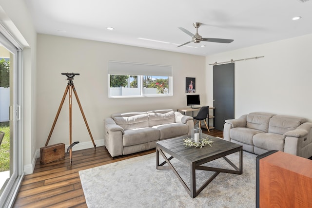 living room featuring a barn door, baseboards, a ceiling fan, wood finished floors, and recessed lighting