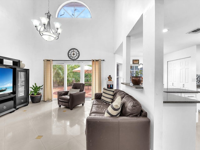 living room with a towering ceiling, light tile patterned floors, visible vents, and an inviting chandelier