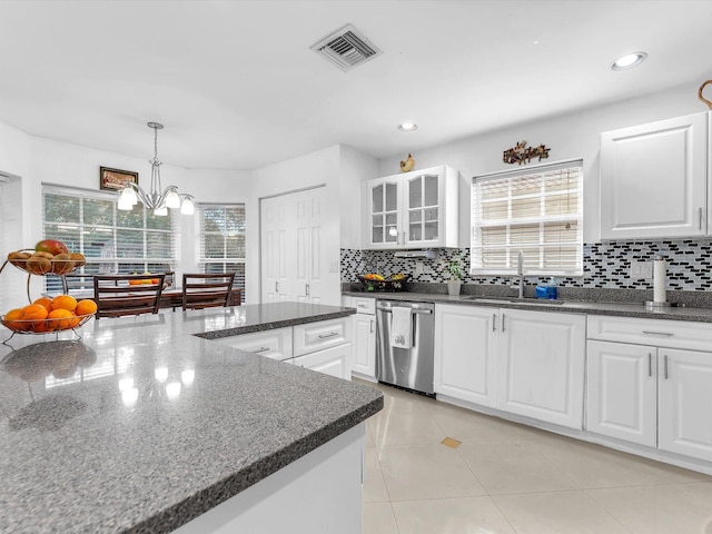 kitchen featuring tasteful backsplash, visible vents, glass insert cabinets, stainless steel dishwasher, and a sink
