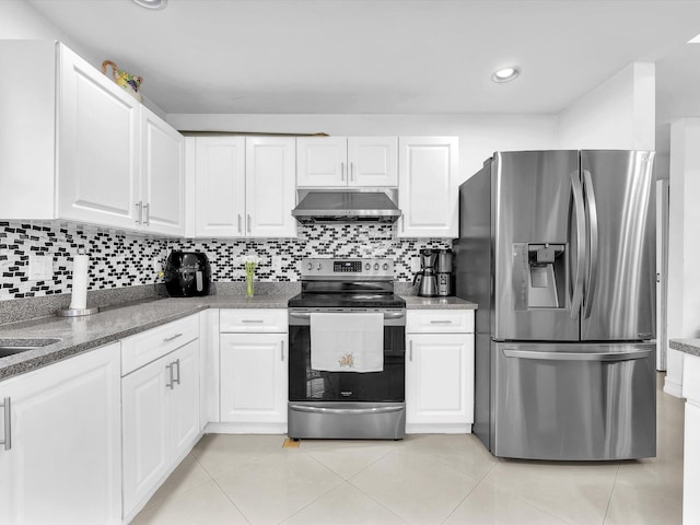 kitchen featuring light tile patterned floors, under cabinet range hood, stainless steel appliances, white cabinetry, and tasteful backsplash