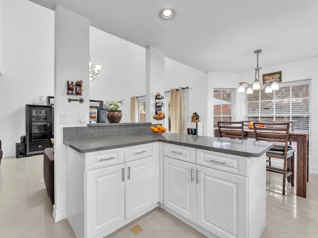 kitchen with dark countertops, white cabinets, a notable chandelier, and light tile patterned flooring
