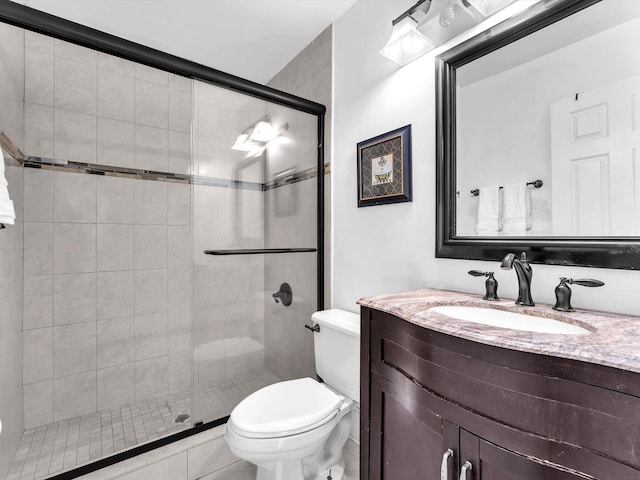 full bathroom with a stall shower, vanity, and toilet